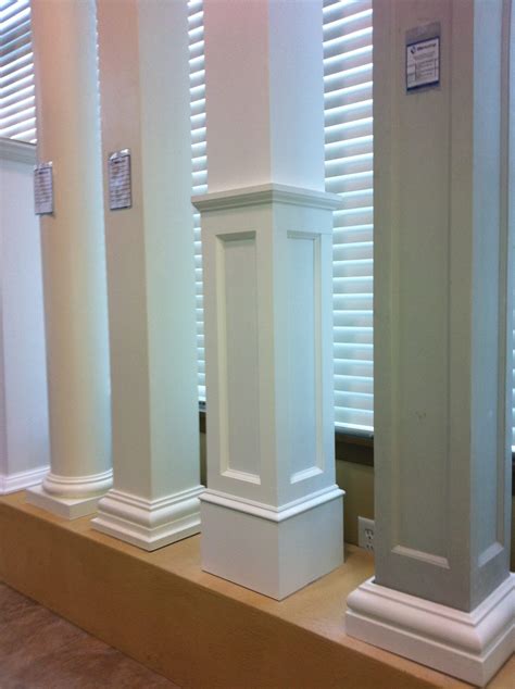 three tall white pillars sitting next to each other on a wooden shelf in front of windows