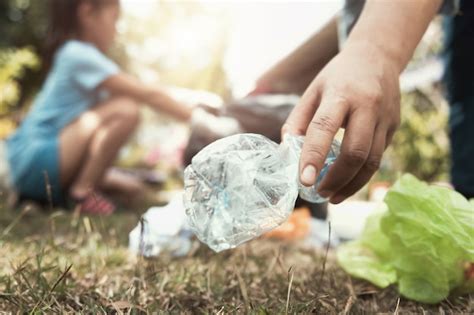 Premium Photo | Woman hand picking up trash bottle for cleaning at park