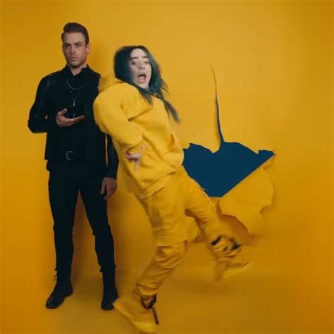 two men standing next to each other in front of a yellow background with an image of a shark