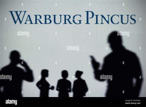 The Warburg Pincus logo is seen on an LED screen in the background while a silhouetted person ...