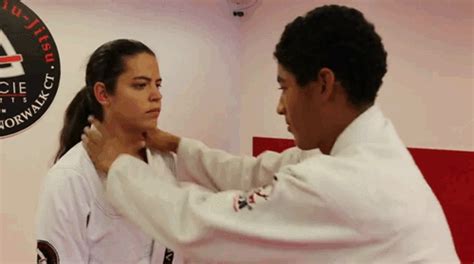 a man helping a woman put on her karate uniform