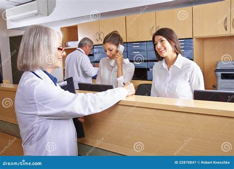 Senior Doctor Talking With Receptionist Royalty Free Stock Photography - Image: 32870847