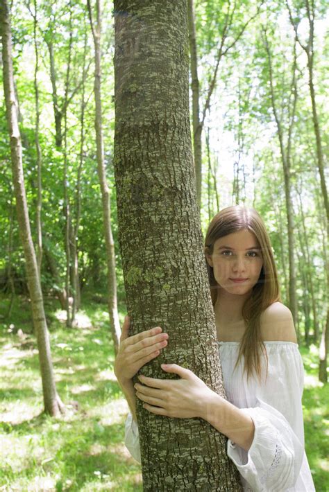 Young woman hugging tree, portrait - Stock Photo - Dissolve