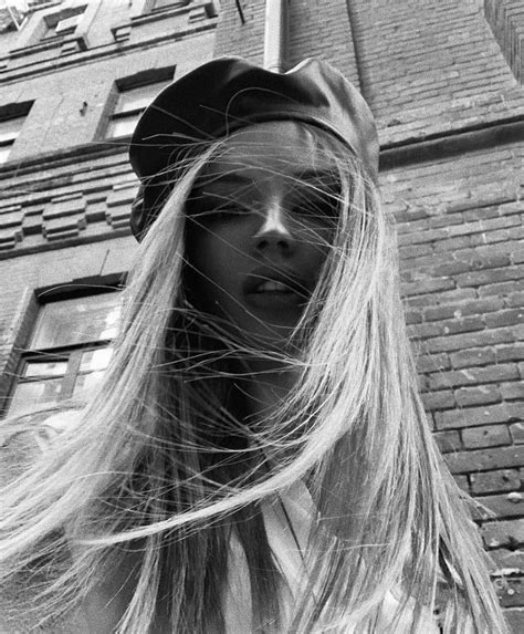 a woman with long hair standing in front of a brick building