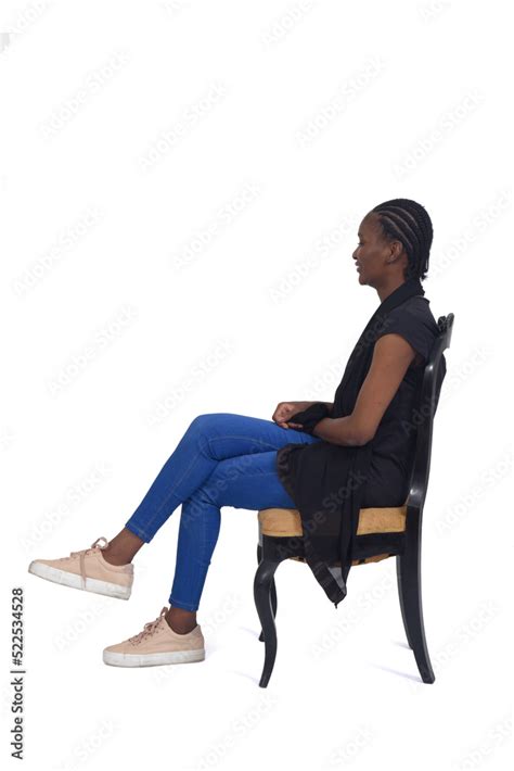 side view of a full portrait of a woman sitting on chair cross-legged over white background ...