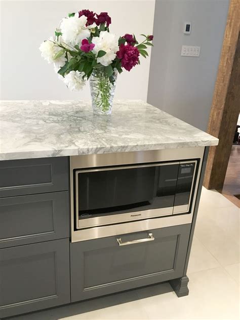 a vase with flowers sitting on top of a kitchen counter next to a ...