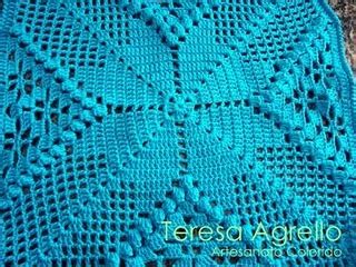 a blue crocheted blanket sitting on top of a wooden floor