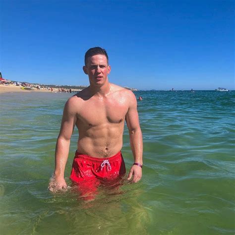 a man standing in the ocean wearing red swim trunks