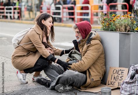 Young woman giving money to homeless beggar man sitting in city. Stock-Foto | Adobe Stock