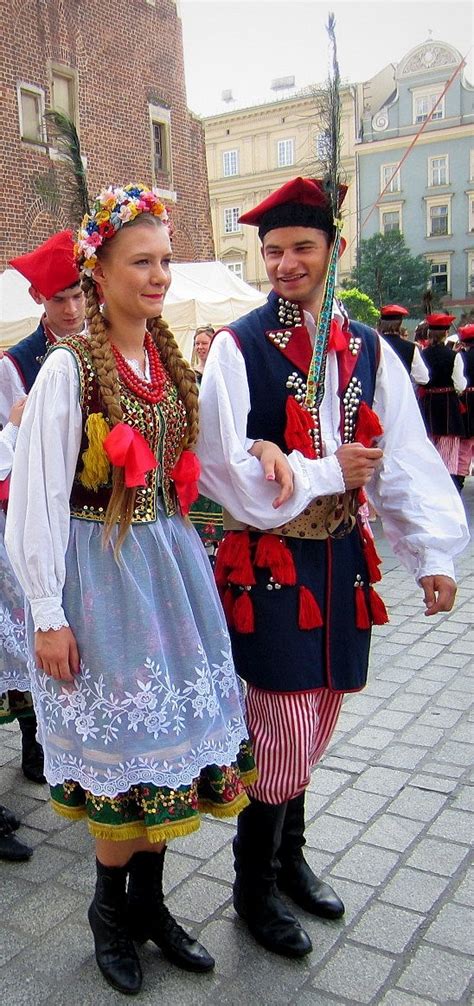 two people dressed in traditional clothing standing next to each other on a brick sidewalk with ...