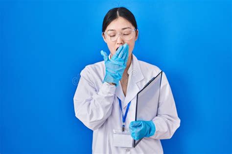 Chinese Young Woman Working at Scientist Laboratory Bored Yawning Tired Covering Mouth with Hand ...