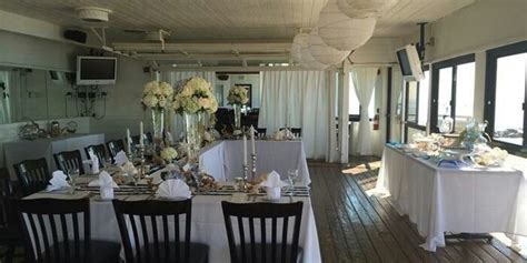 a dining room filled with lots of tables covered in white tablecloths and centerpieces