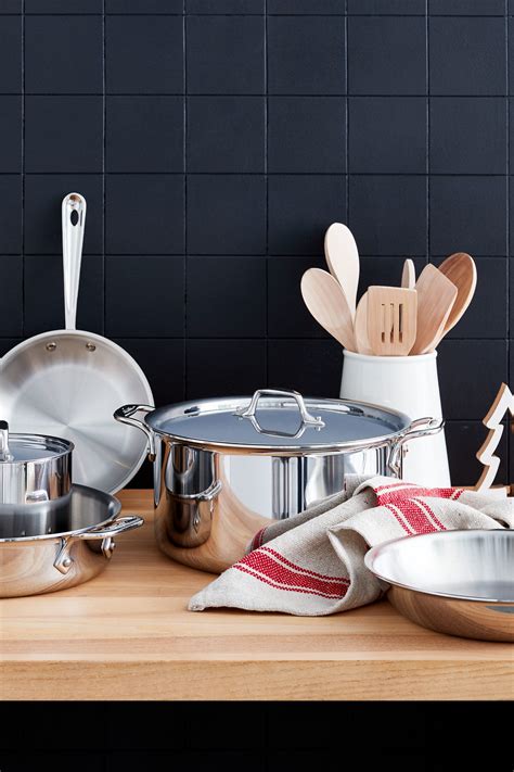 stainless steel pots and pans with wooden utensils sitting on a counter top