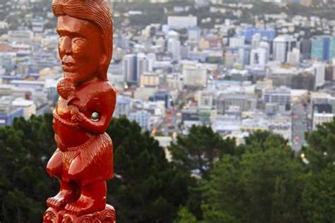 a red statue on top of a hill with a city in the background