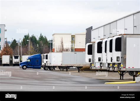 Big rig blue semi truck and refrigerated semi trailers standing in row ...