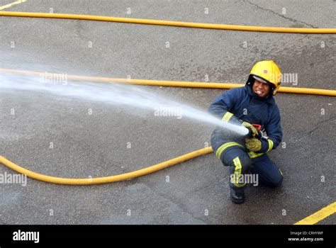 A fire fighter uses a water hose to douse a fire Stock Photo - Alamy