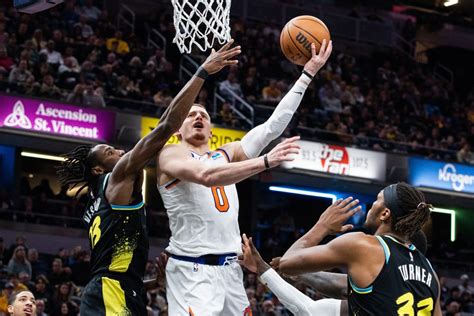 New York Knicks guard Donte DiVincenzo (0) shoots the ball while Indiana Pacers forward Aaron ...