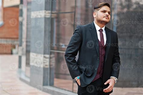 Stylish indian businessman in formal wear standing against windows in ...