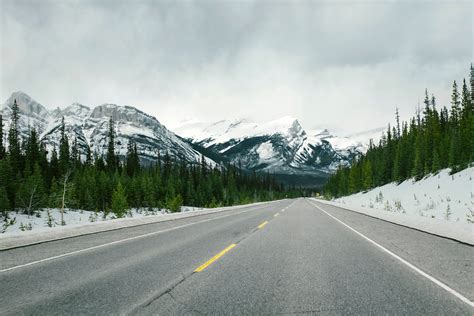 Road with snow-capped mountains with trees and landscape in Jasper National Park, Alberta ...