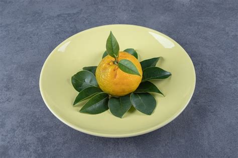 Free Photo | Fresh organic tangerine with leaves on yellow plate.