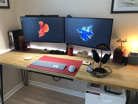 two computer monitors sitting on top of a wooden desk