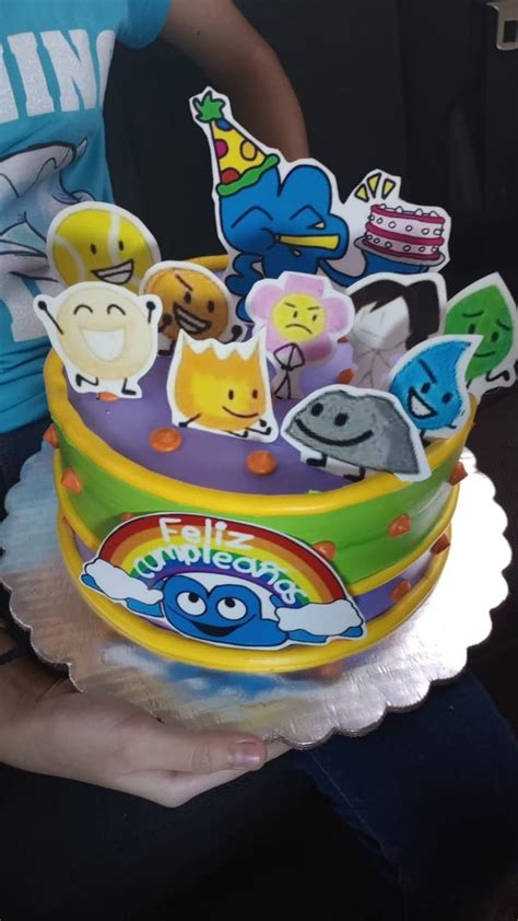 a person holding a birthday cake with many stickers on it's top and bottom