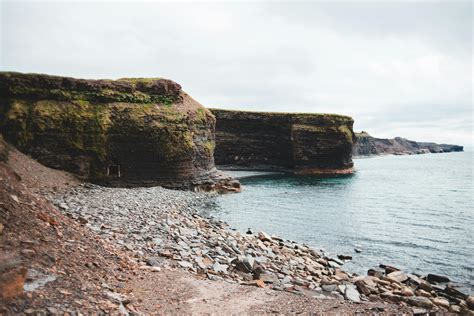 Brown and Green Rock Formation Beside Body of Water · Free Stock Photo