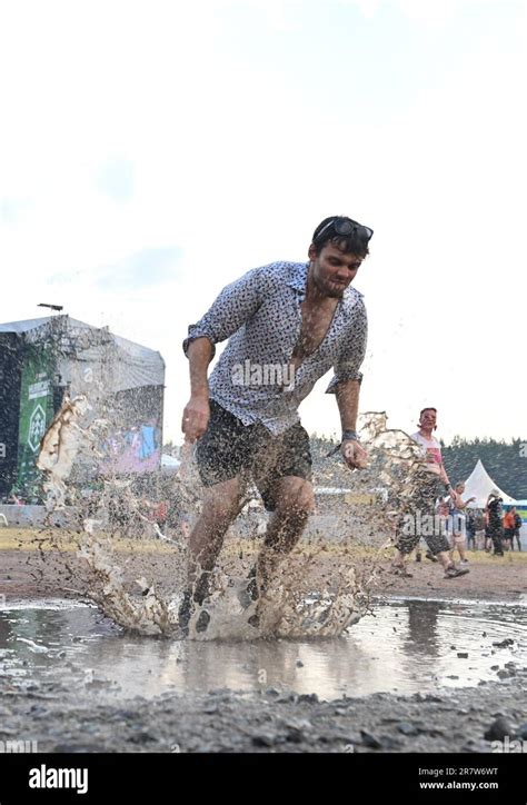 17 June 2023, Lower Saxony, Scheeßel: A festival visitor jumps into a puddle at the Hurricane ...