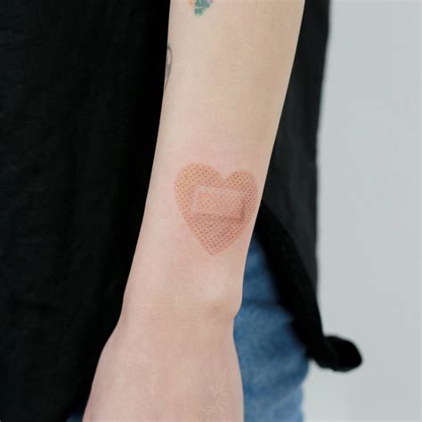 Heart shaped bandage tattoo on the wrist