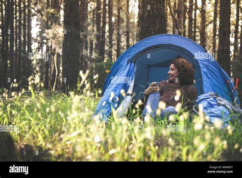 Travel blogger woman sitting in a camping tent. Tourist smiling girl enjoying sunset alone in ...