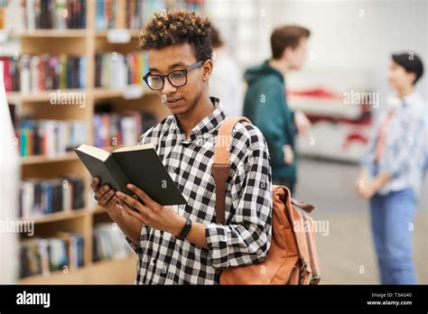 Intelligent guy reading book in library Stock Photo - Alamy