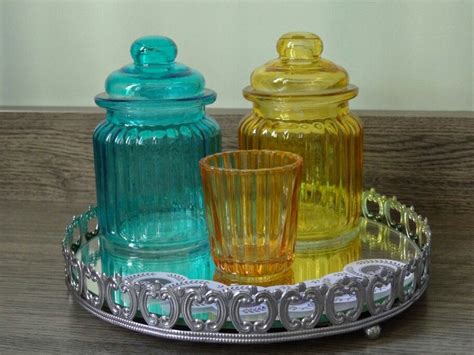 three different colored glass jars on a tray with silver trimmings and metal handles