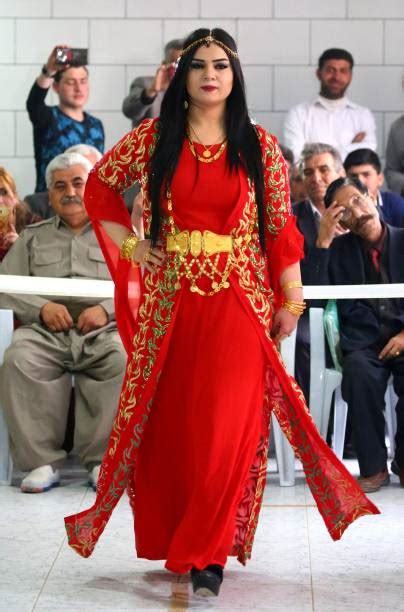 A Syrian-Kurdish woman models traditional Kurdish attire during a ...