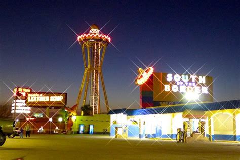 the neon lights shine brightly in front of a building with a tall tower at night