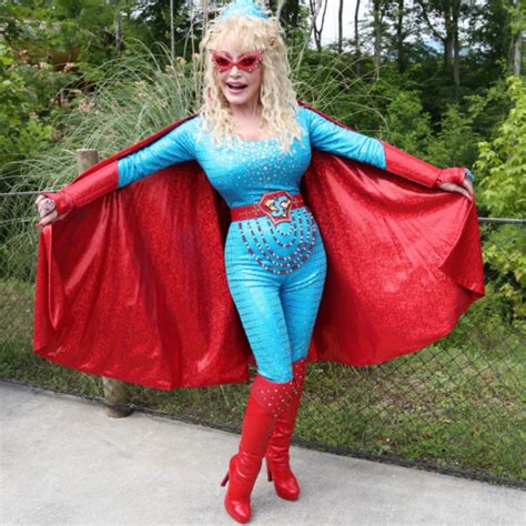 a woman dressed in blue and red posing for the camera with a cape on ...