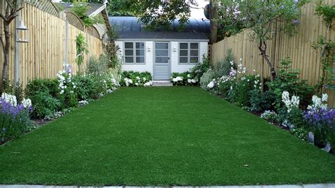 Artificial easy grass lawn summer house sandstone paving and white flower planting scheme London ...