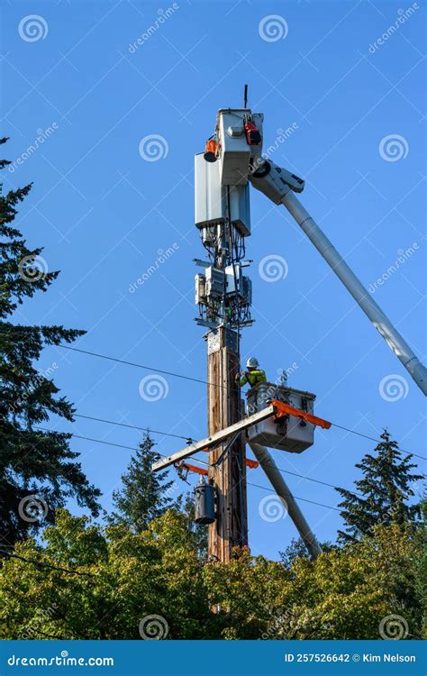 Two Linemen Working on a Wireless Communications Radio and Antenna Installation Using a Bucket ...