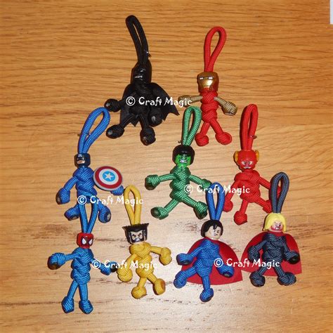 several small plastic keychains are sitting on a wooden table, one has an iron man figure and ...