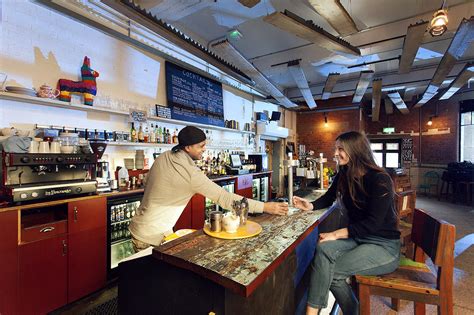 Barrister serving coffee to a lady seating at the bar and smiling at each other.