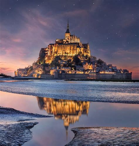 A night-lit Mont Saint Michel reflecting off the low tide : MostBeautiful