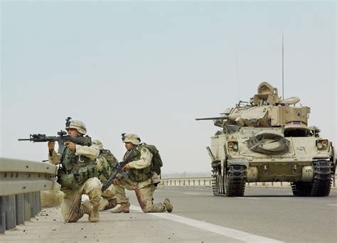 Soldiers of the 1st Infantry Division, supported by a Bradley fighting vehicle of the 82nd ...