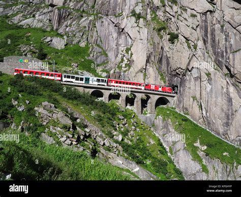 Red express train on scenic stony St. Gotthard railway bridge and ...