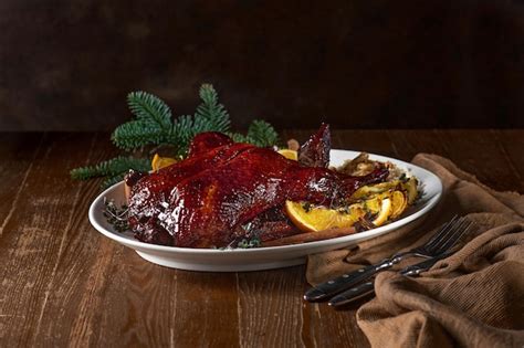 Premium Photo | Roasted christmas duck with green tree branch on wooden ...