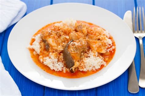 Premium Photo | Fish stew with rice on white plate on wooden surface