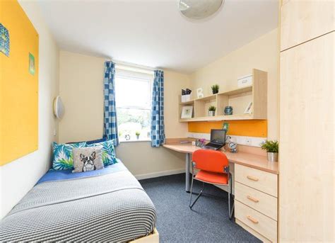 a bedroom with a bed, desk and chair in the corner next to a window