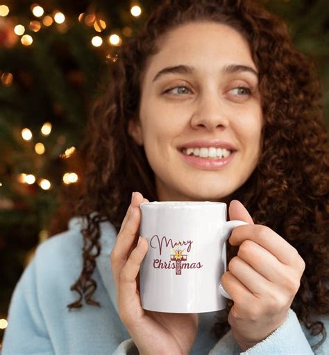 a woman holding a coffee mug in front of a christmas tree