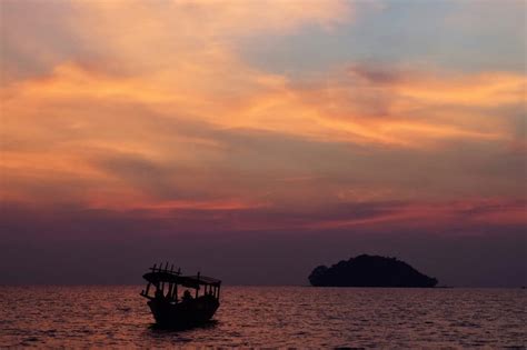 Sunset and boat in Cambodia - Two Tall Travellers