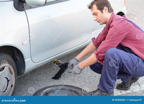 Man Changing a Flat Tire on the Side of the Road Stock Image - Image of safety, adult: 99200287