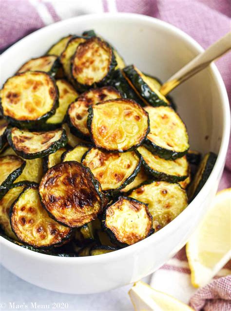 a white bowl filled with cooked zucchini on top of a purple and white towel