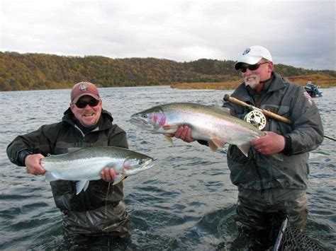 two men standing in the water holding fish